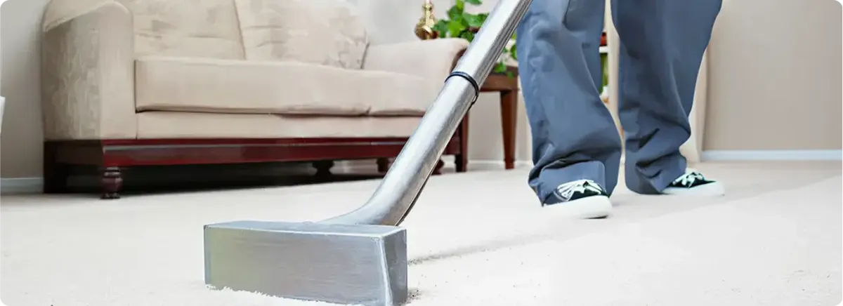 Carpet cleaning technician using a hot-water extraction wand on a light-colored carpet in a living room, Santa Ana, CA.